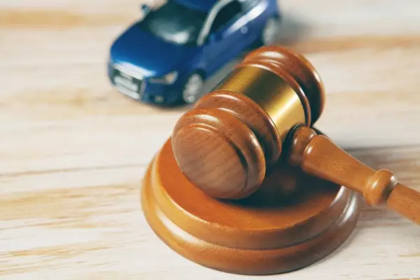 Judge gavel and toy car on white textured background